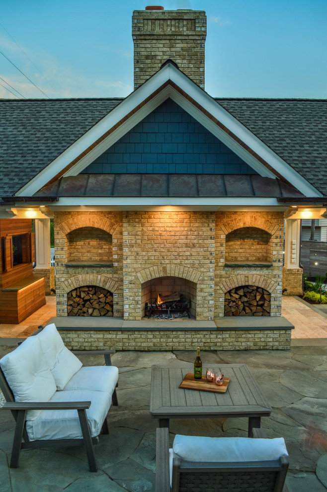 Immagine di un grande patio o portico american style dietro casa con un caminetto, pavimentazioni in pietra naturale e un gazebo o capanno