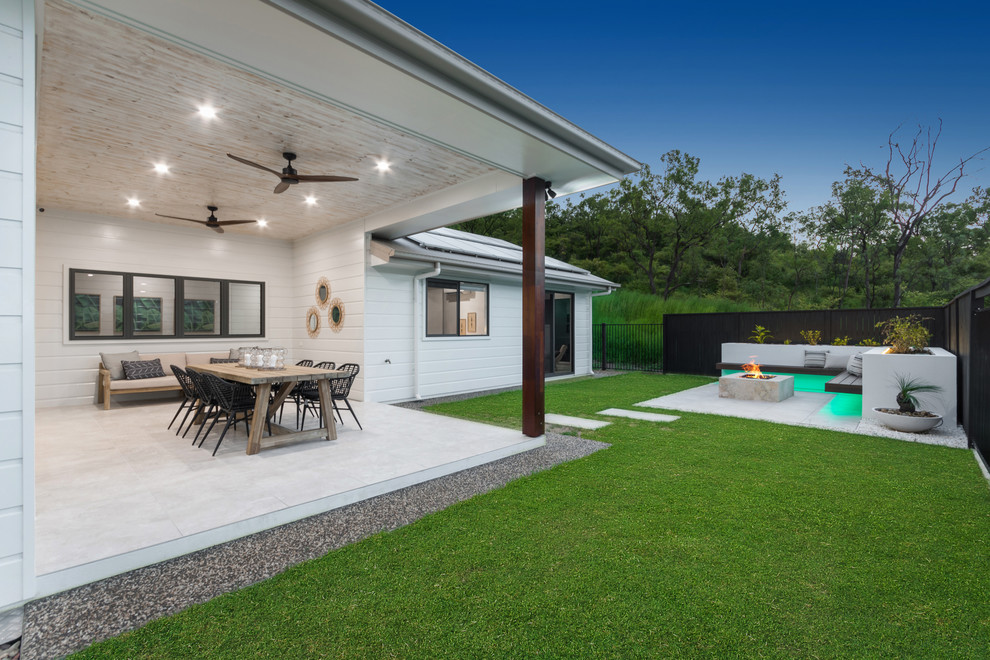 Design ideas for a large modern back patio in Townsville with a fire feature, concrete paving and a roof extension.