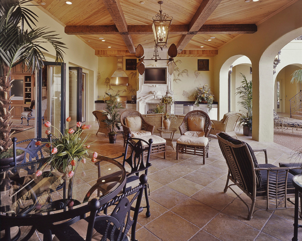 Cette photo montre une grande terrasse arrière chic avec une cuisine d'été, des pavés en pierre naturelle et une extension de toiture.