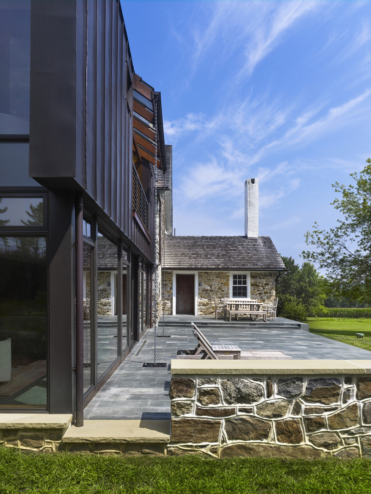 Photo of a contemporary back patio in Philadelphia with a water feature, natural stone paving and no cover.