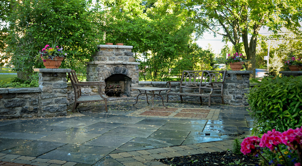 Esempio di un patio o portico country dietro casa con un focolare e pavimentazioni in cemento