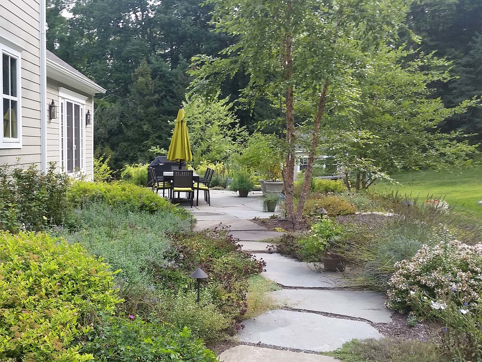 Foto de patio de estilo de casa de campo en patio trasero con adoquines de piedra natural