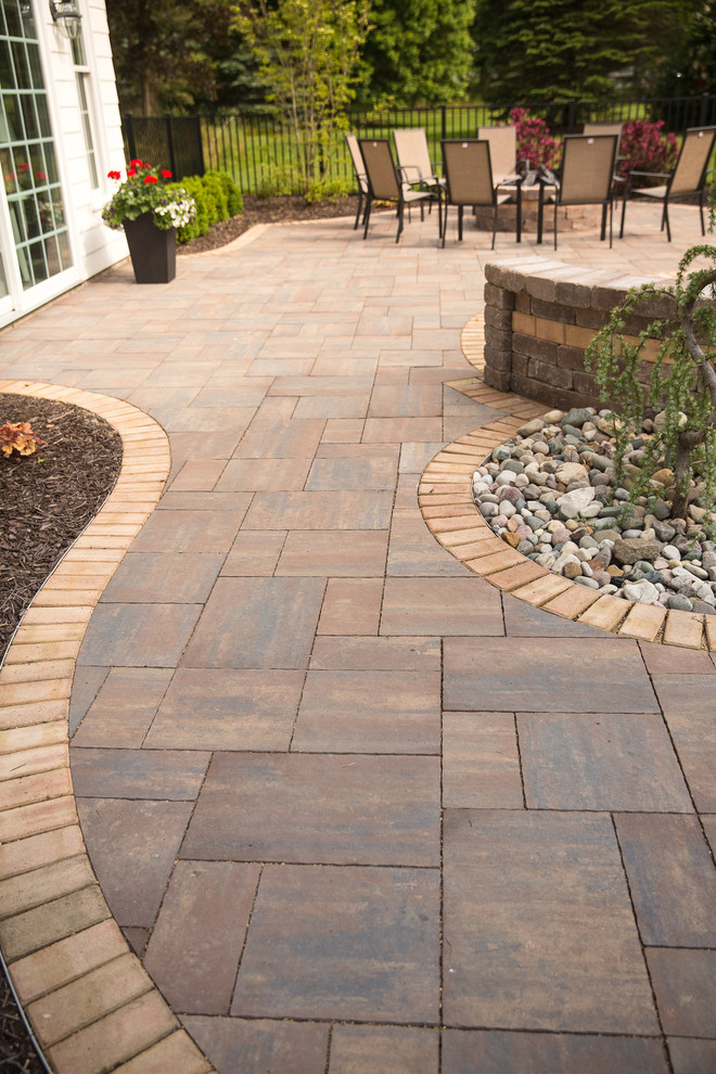 This is an example of a large country back patio in Grand Rapids with a fire feature and natural stone paving.
