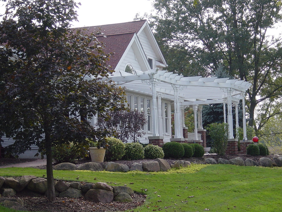 Exemple d'une grande terrasse avant nature avec des pavés en brique et une pergola.