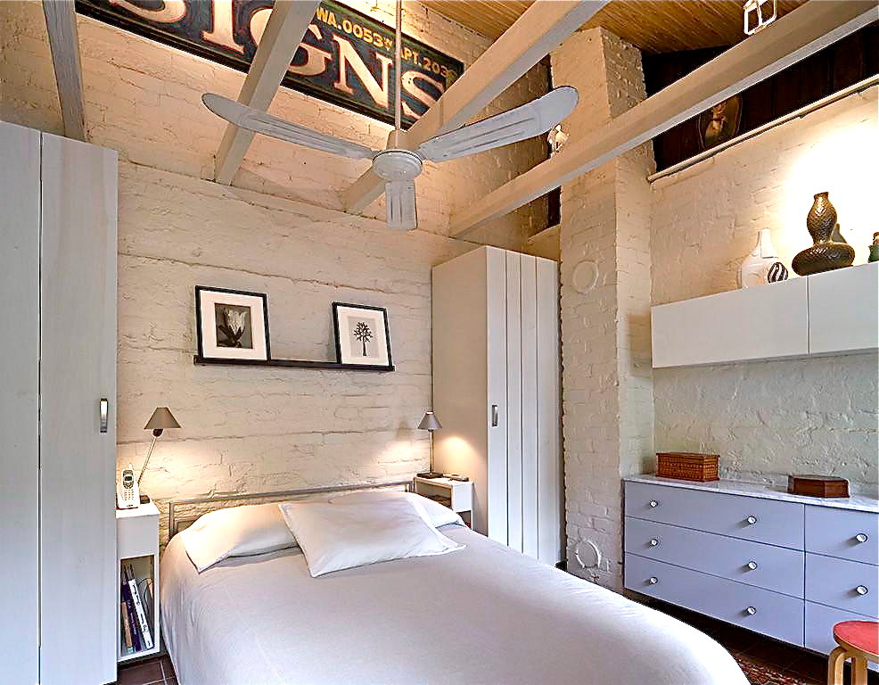 Modelo de dormitorio principal bohemio pequeño con paredes blancas, suelo de baldosas de cerámica y marco de chimenea de ladrillo