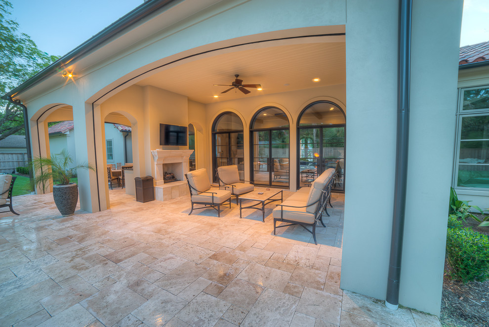 Immagine di un patio o portico tropicale di medie dimensioni e dietro casa con un focolare, piastrelle e un tetto a sbalzo