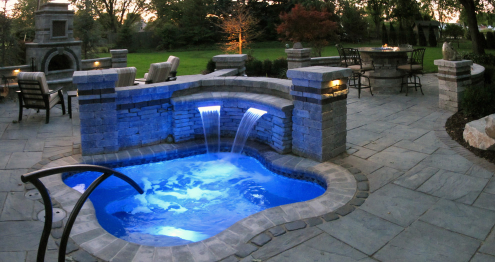This is an example of a large rustic back swimming pool in Detroit with natural stone paving.