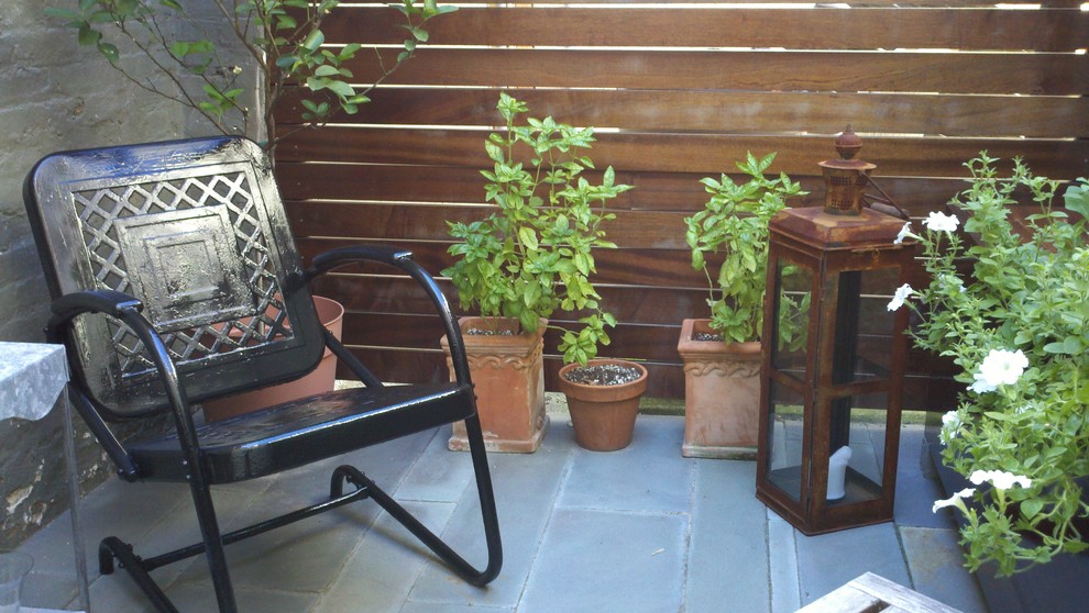 Design ideas for a small contemporary back patio in Baltimore with a potted garden, natural stone paving and no cover.