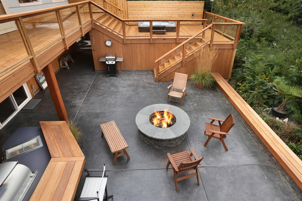 Diseño de patio de estilo americano en patio trasero con brasero y suelo de hormigón estampado