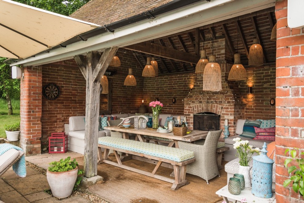 This is an example of a bohemian back patio in Hampshire with a roof extension and a fireplace.