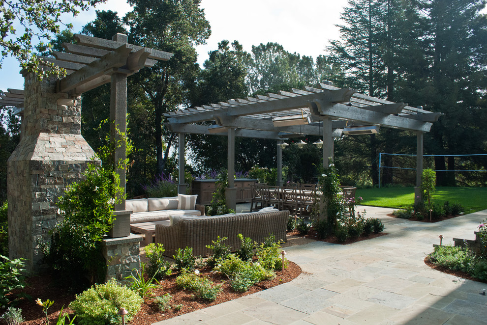 This is an example of an expansive traditional back patio in San Francisco with a fire feature and natural stone paving.