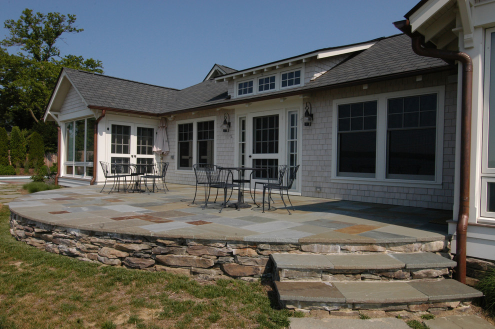 Immagine di un ampio patio o portico stile rurale dietro casa con pavimentazioni in pietra naturale e nessuna copertura