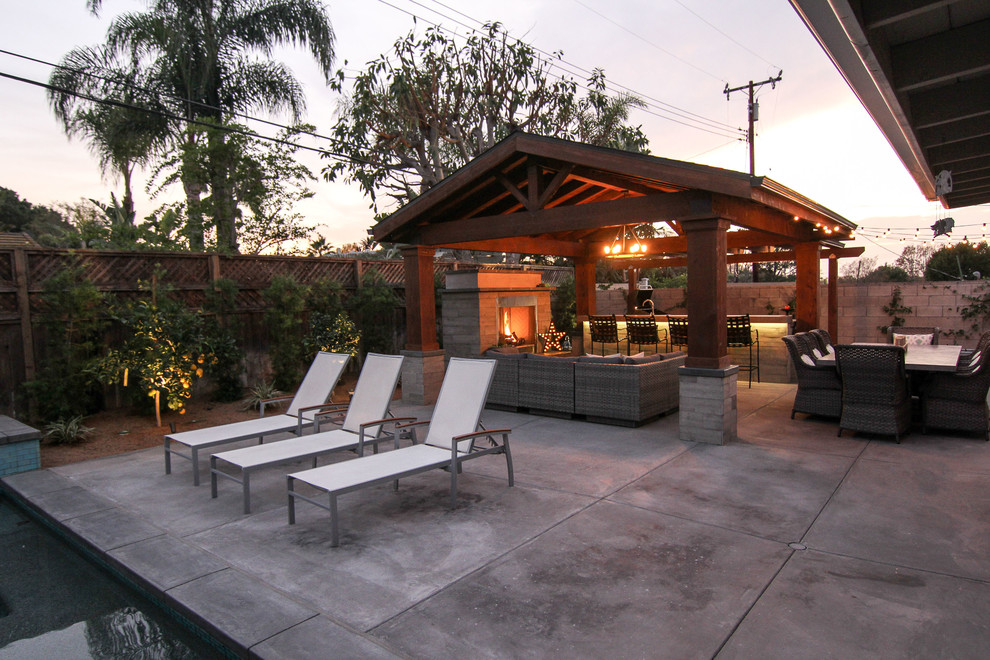 Cette photo montre une grande terrasse arrière chic avec une cuisine d'été, des pavés en pierre naturelle et un gazebo ou pavillon.