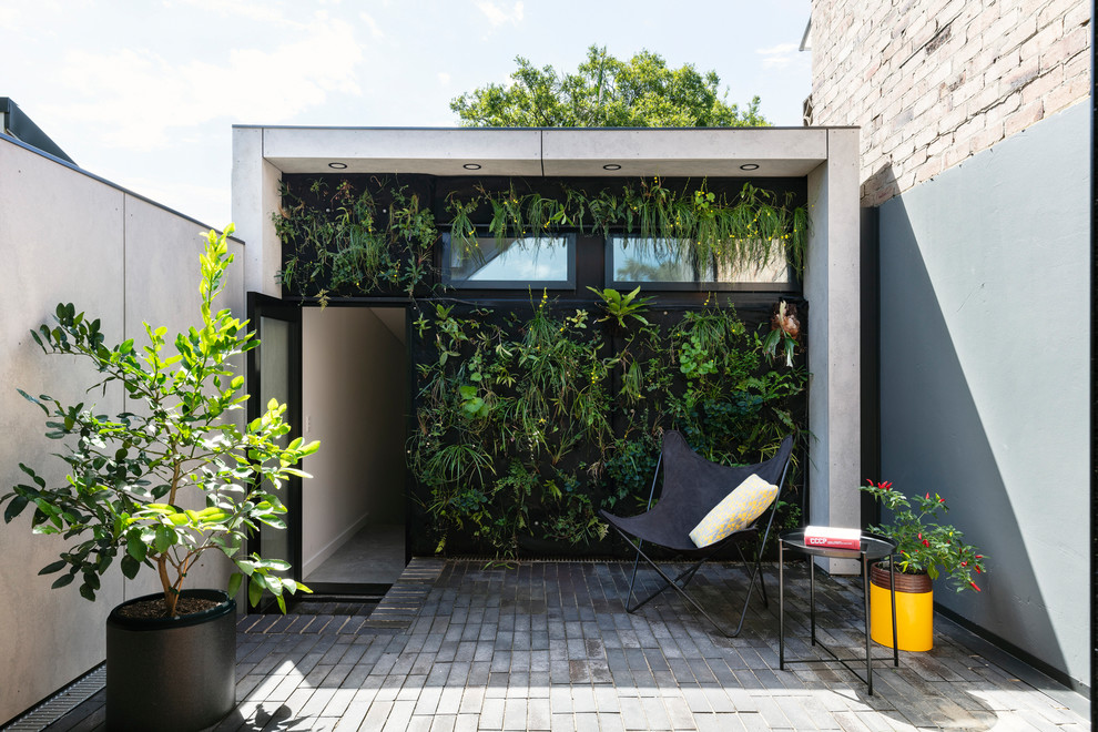 На фото: двор среднего размера на внутреннем дворе в современном стиле с мощением клинкерной брусчаткой и вертикальным садом без защиты от солнца