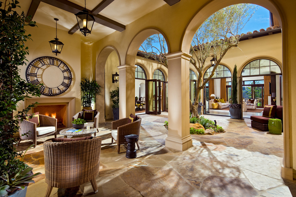 Photo of an expansive mediterranean courtyard patio in Orange County with a roof extension.