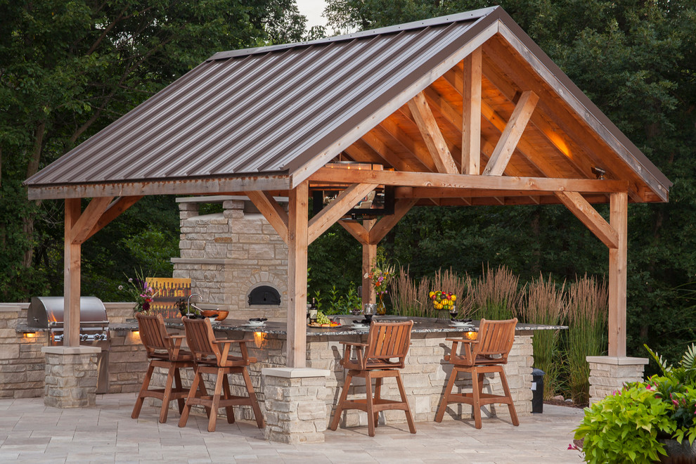 Imagen de patio clásico grande en patio trasero con adoquines de piedra natural y cenador