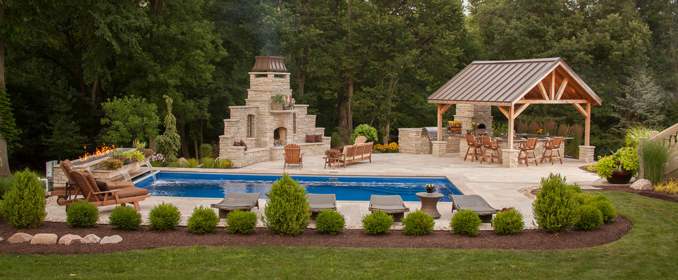 Cette photo montre une grande terrasse arrière tendance avec un foyer extérieur, des pavés en pierre naturelle et une pergola.