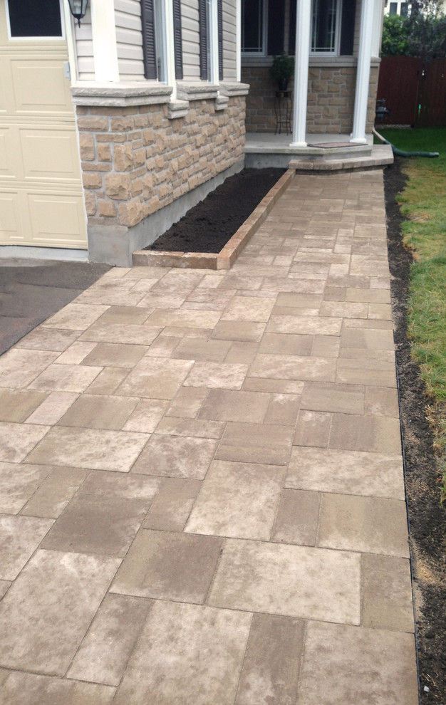 Medium sized modern front patio in Ottawa with brick paving.