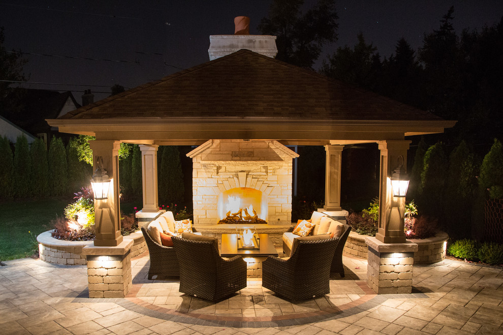 This is an example of a large modern back patio in Chicago with a fire feature, natural stone paving and a gazebo.