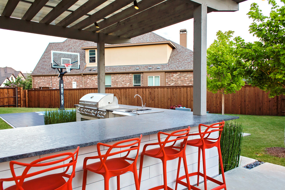 Cette photo montre une grande terrasse arrière éclectique avec une cuisine d'été, des pavés en béton et une pergola.