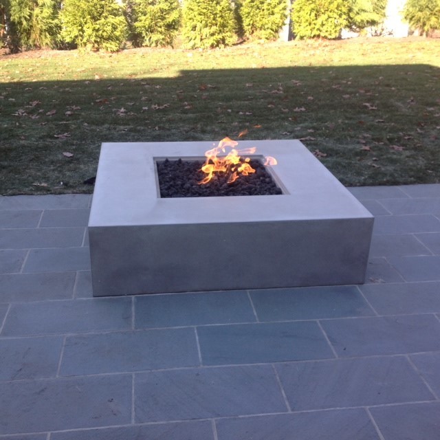 Modern back patio in New York with a fire feature, tiled flooring and no cover.