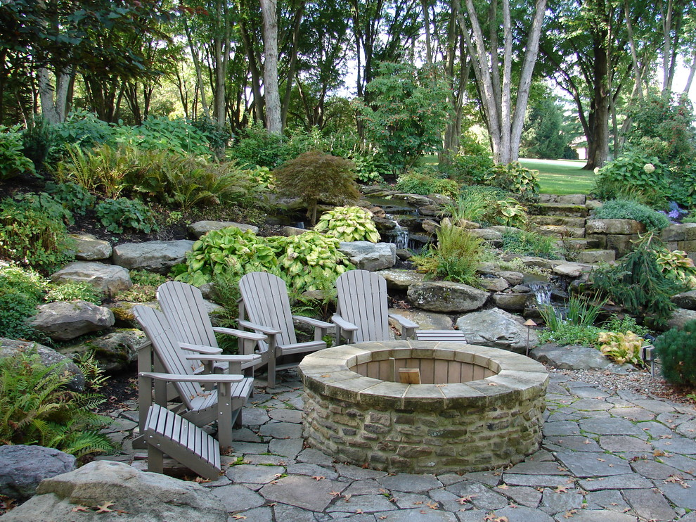 Example of a large mountain style backyard stone patio design in Cleveland with a fire pit and no cover