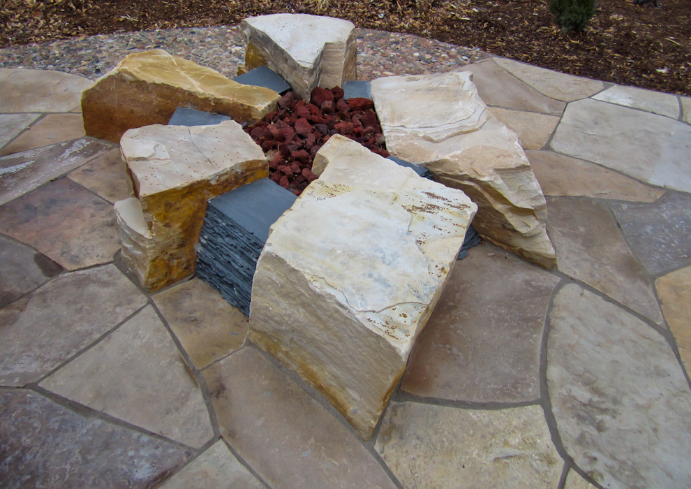 Ejemplo de patio rústico grande sin cubierta en patio lateral con brasero y adoquines de piedra natural