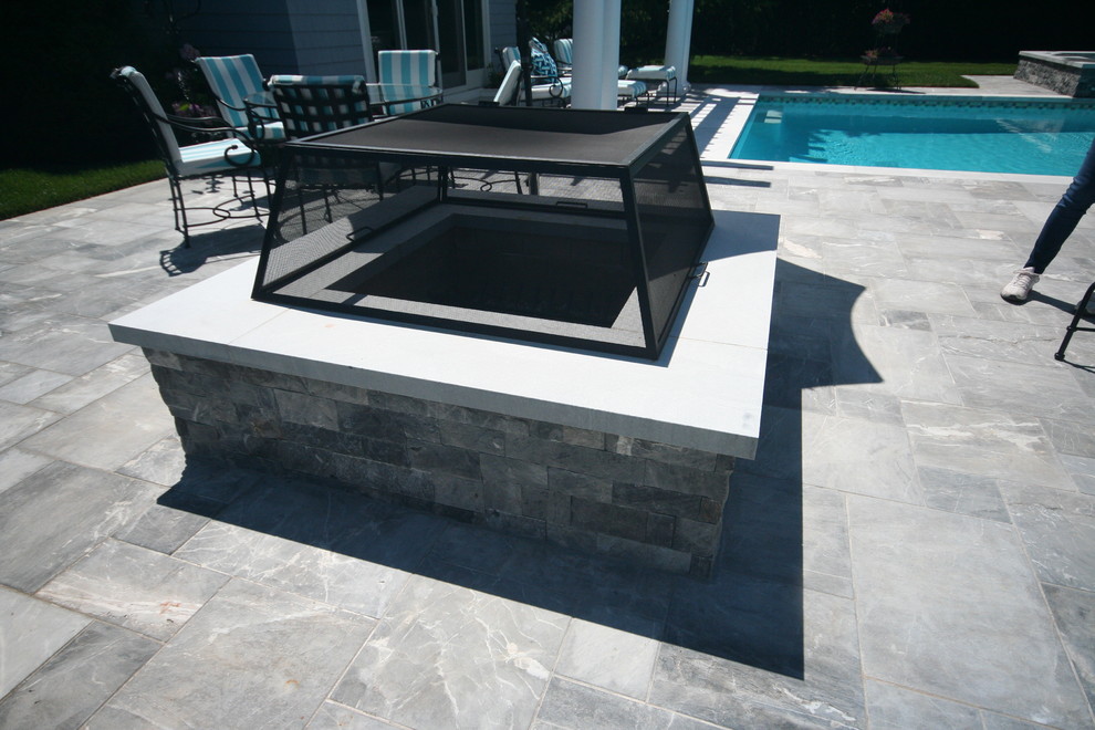 Photo of a large contemporary side patio in New York with a fire feature, natural stone paving and no cover.