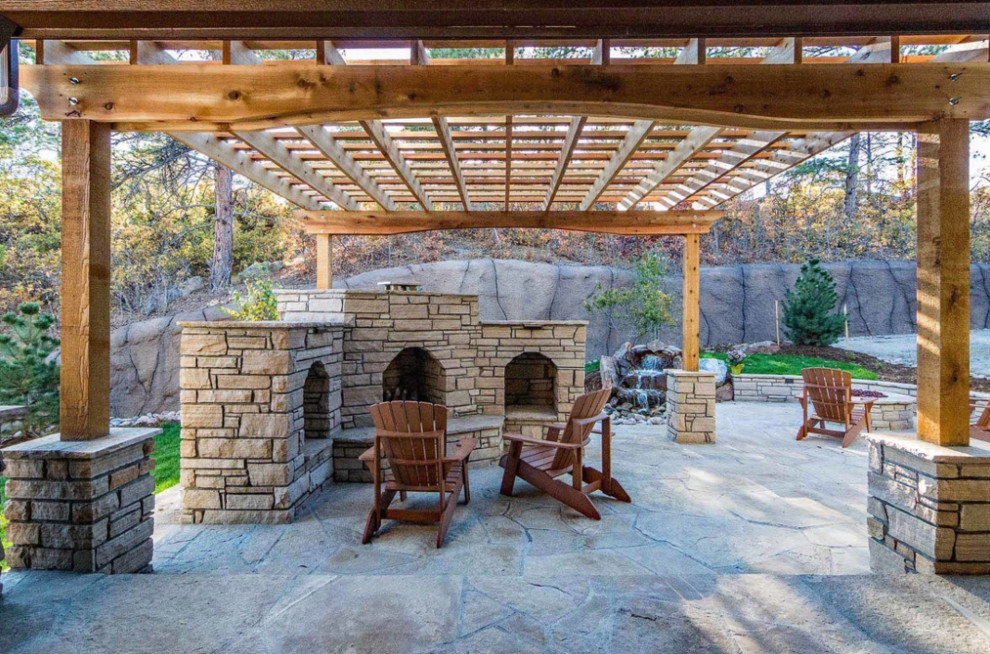 Cette image montre une grande terrasse arrière design avec un foyer extérieur et des pavés en pierre naturelle.