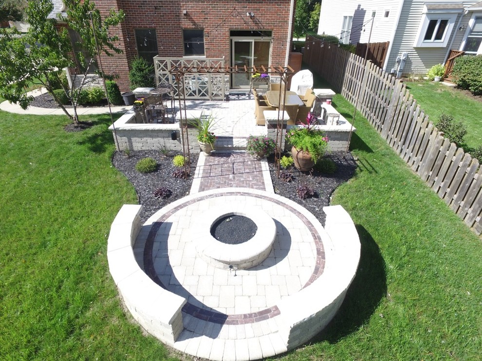 Large elegant backyard stone patio photo in Chicago with a fire pit and no cover
