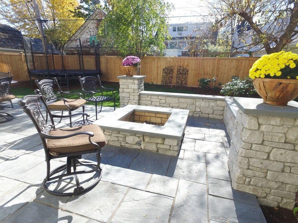 Design ideas for a large classic back patio in Chicago with a fire feature, natural stone paving and no cover.