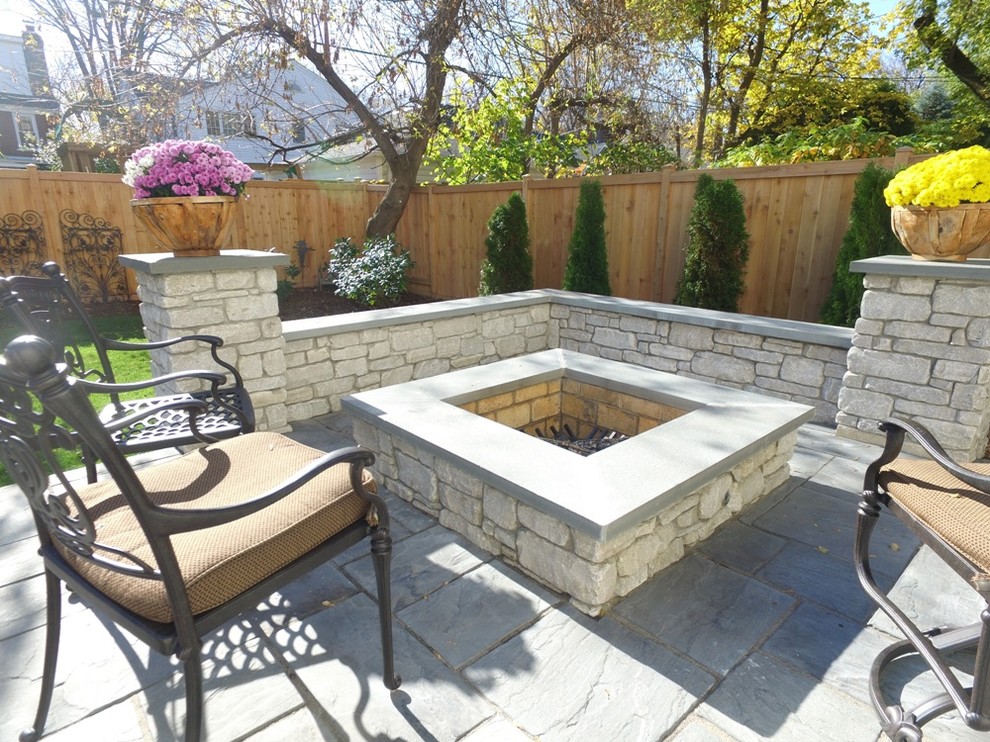 Imagen de patio clásico grande sin cubierta en patio trasero con brasero y adoquines de piedra natural