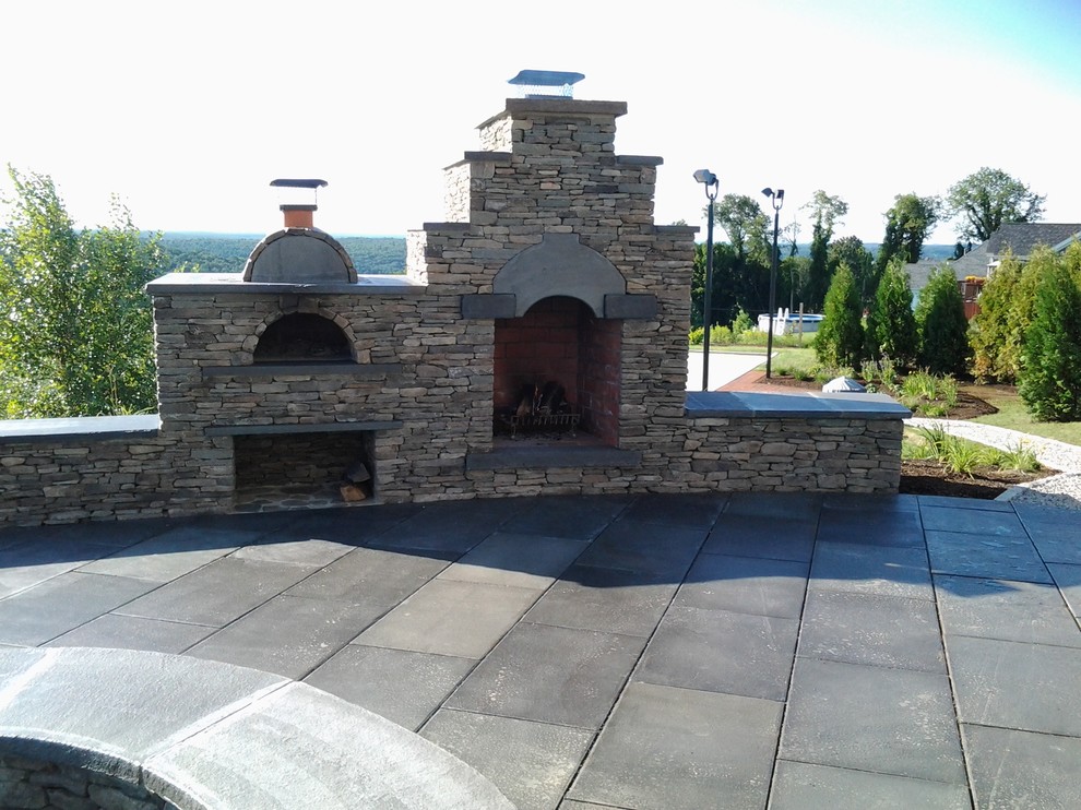 Example of a classic backyard stone patio design in Boston with a fire pit