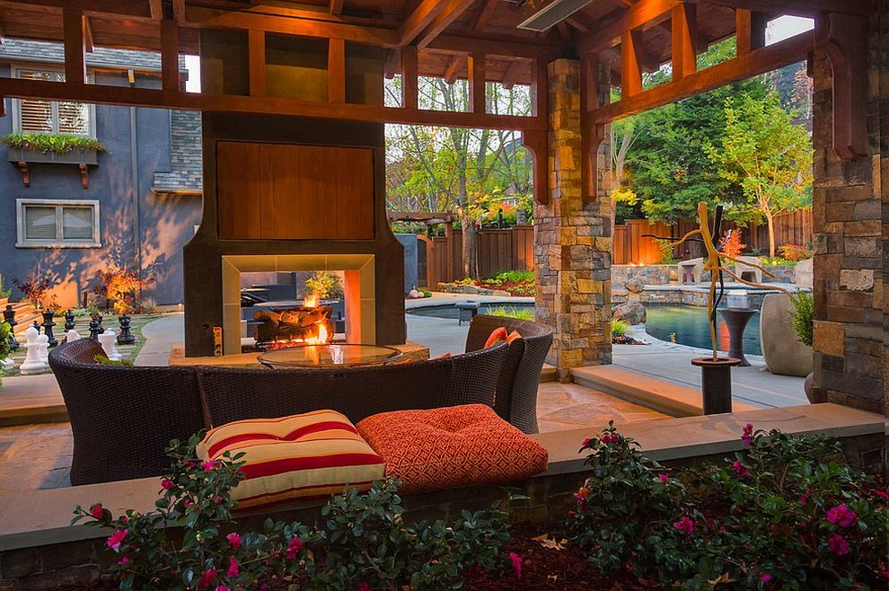 Immagine di un grande patio o portico stile americano dietro casa con pavimentazioni in pietra naturale, un gazebo o capanno e un focolare