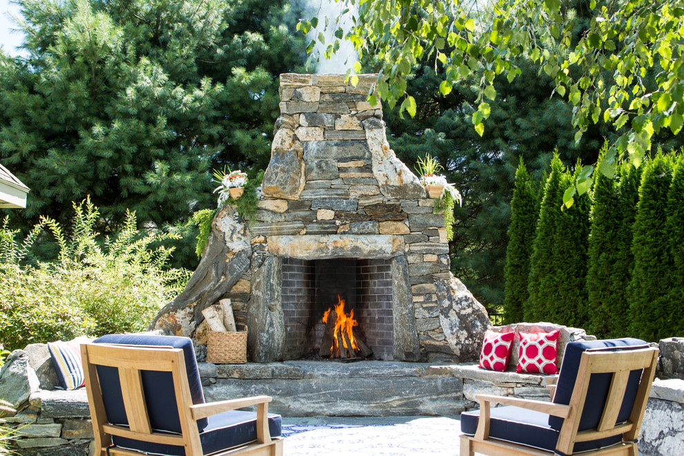 Large rustic back patio in New York with a fire feature, natural stone paving and no cover.