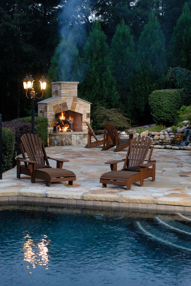 This is an example of a large classic back patio in Atlanta with a fire feature, natural stone paving and no cover.