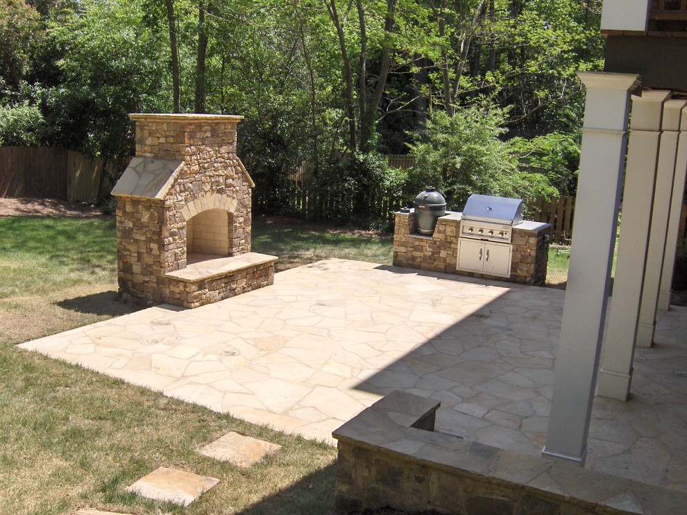 Example of a large classic backyard stone patio kitchen design in Atlanta with a pergola