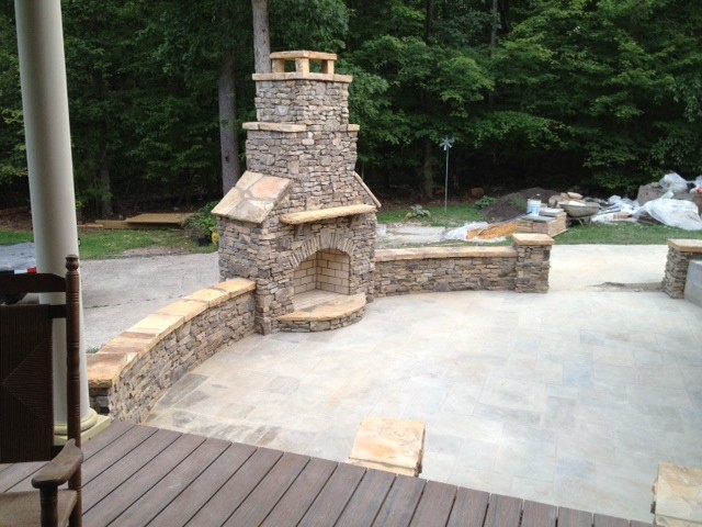 Example of a large mountain style backyard stone patio design in Raleigh with a fire pit and no cover