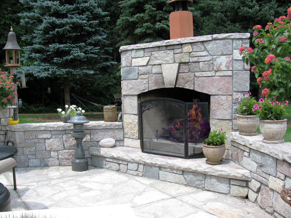Large elegant backyard stone patio photo in Other with a fire pit