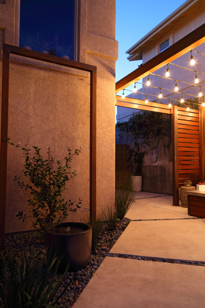 Immagine di un piccolo patio o portico minimalista in cortile con un focolare, lastre di cemento e una pergola