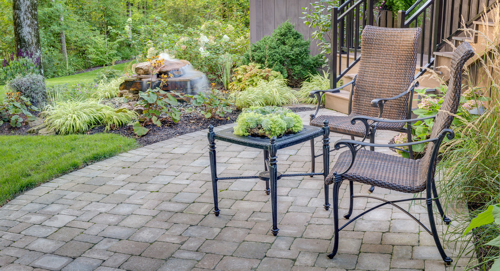 Modelo de patio clásico de tamaño medio sin cubierta en patio trasero con adoquines de ladrillo y fuente