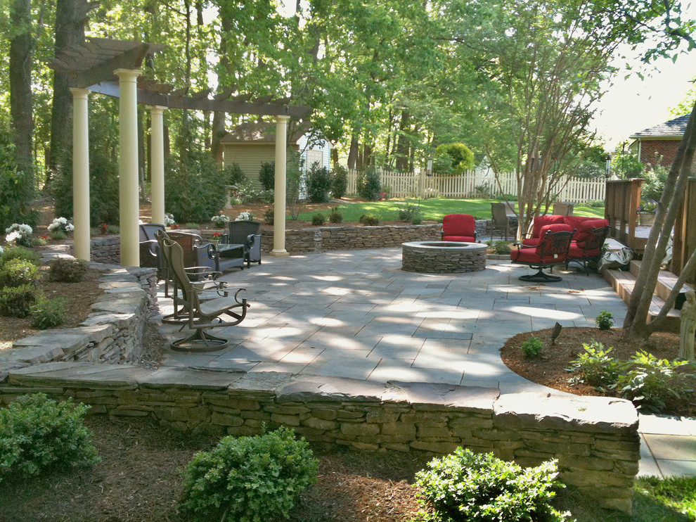 Ejemplo de patio clásico de tamaño medio en patio trasero con brasero, adoquines de piedra natural y pérgola