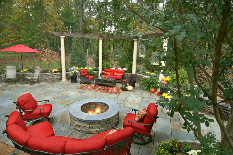 Immagine di un patio o portico chic di medie dimensioni e dietro casa con un focolare, pavimentazioni in pietra naturale e una pergola
