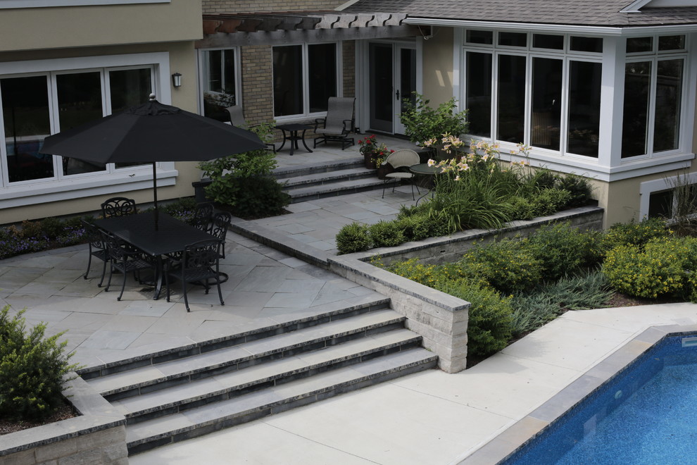 Esempio di un grande patio o portico classico dietro casa con pavimentazioni in pietra naturale e una pergola