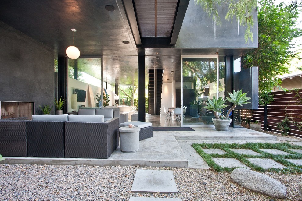 Idée de décoration pour une terrasse design de taille moyenne avec un foyer extérieur, une dalle de béton, une extension de toiture et une cour.