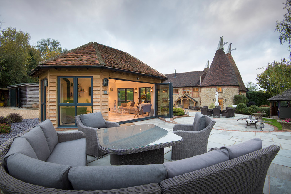 Inspiration for an expansive contemporary back patio in Buckinghamshire with natural stone paving and no cover.