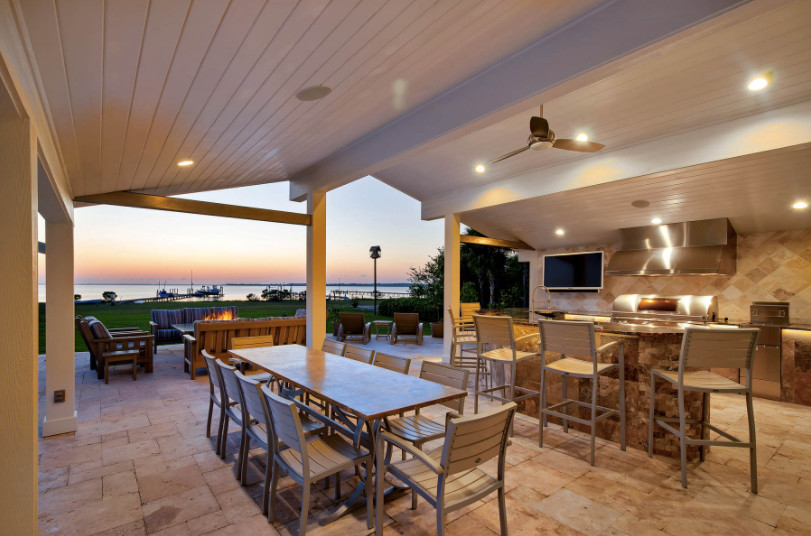 Cette image montre une grande terrasse arrière traditionnelle avec une cuisine d'été, du béton estampé et une extension de toiture.