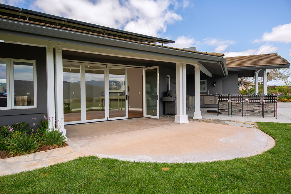 Idée de décoration pour une très grande terrasse arrière champêtre avec une cuisine d'été, des pavés en béton et une extension de toiture.