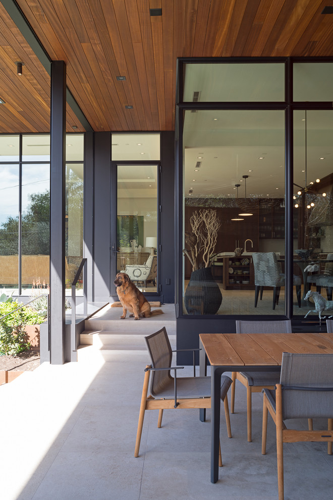 Cette image montre une terrasse arrière design de taille moyenne avec une cuisine d'été, des pavés en pierre naturelle et une extension de toiture.