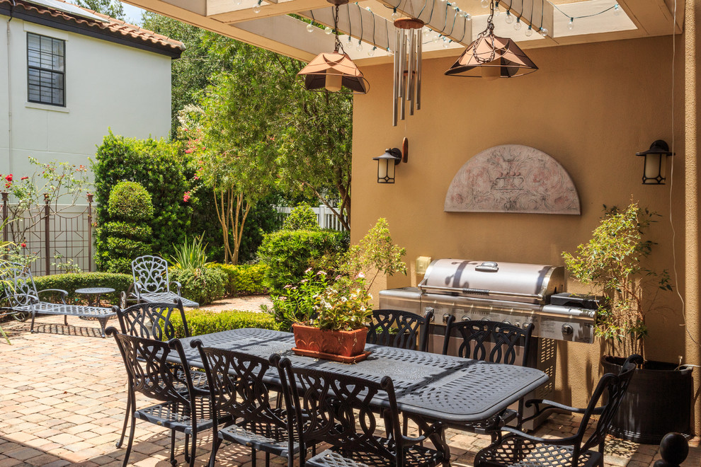 Diseño de patio mediterráneo en patio trasero con adoquines de ladrillo y pérgola